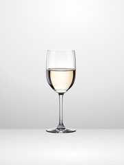 A beautiful wine glass filled with white wine stands out against a light background.