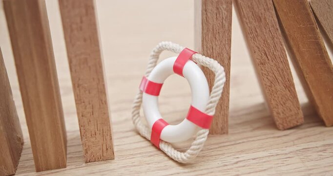 Risk management, crisis prevention, contingency planning, and risk mitigation : A red lifebuoy stands in front of a row of wooden blocks, symbolizing the importance of proactive risk management.