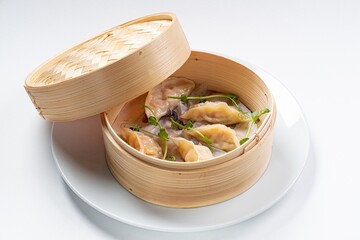 Chinese Gyoza with Sauce in Wooden Dish Against a White Background