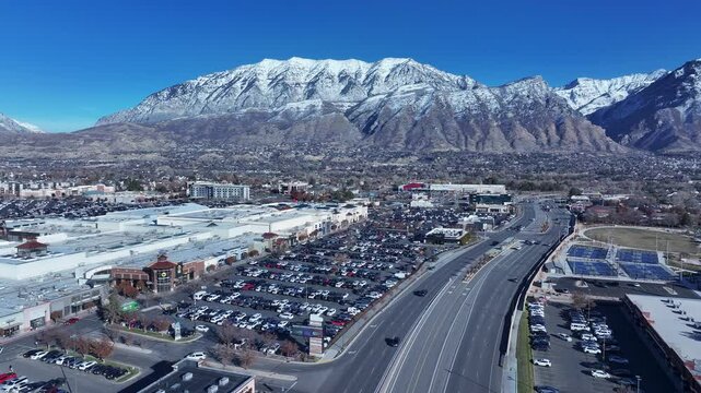 Aerial highway traffic business mountain snow Utah. Orem city, variety of stores businesses. Urban economy Malls, stores, residential neighborhoods, parks. High desert valley. Snow covered winter.