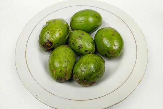 Kedondong is also known as ambarella fruit or otaheite apple or hot plum, which is delicious on a white plate on a wooden table.