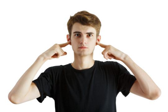 Young man wearing aT-shirt, plugging his ears with fingers, standing against a white background. Concept of ignoring or blocking out sound