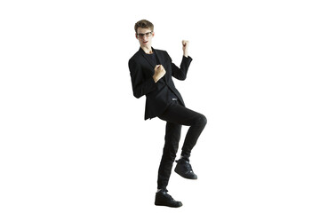 Man in a dynamic celebratory pose wearing asuit and glasses, standing on one leg, isolated on a...
