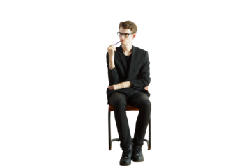 Man inoutfit sitting on a chair, isolated on white background. Clean and minimalistic concept of contemplation, focus, and professionalism