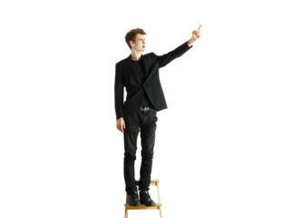 A man in formal attire standing on a wooden stool, pointing upward, isolated on a white background. Concept of leadership, ambition, vision