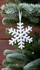 snowflake ornament hanging from a frosted pine branch