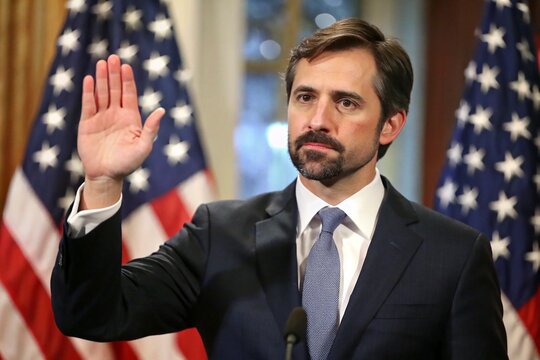 A man in a suit is waving at the camera