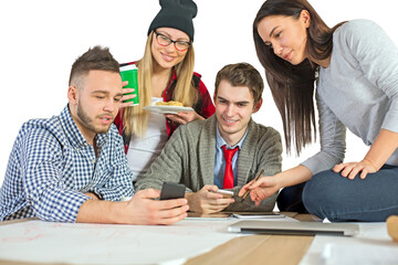 Group of young professionals or students gathered around a table, brainstorming and using technology, isolated on a white background, teamwork concept