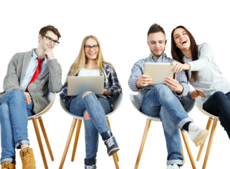 Four young adults sitting on chairs, interacting with laptops and tablets, casual clothing, white background. Concept of teamwork and technology