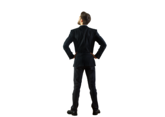 A man in a dark suit viewed from behind, standing with hands on hips, isolated on a clean white background. Concept of confidence, business, and leadership