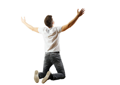 Back view of a man kneeling with arms wide open in a white shirt and jeans on a white background. Concept of freedom and celebration