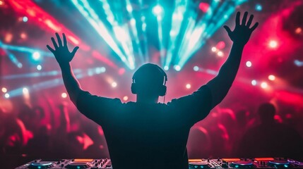 a dj in front of a stage with his hands in the air