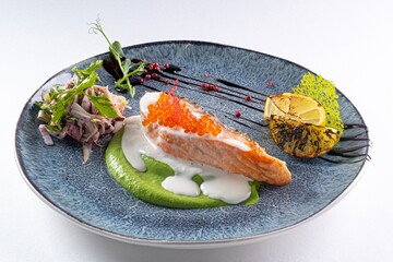 Salmon Steak with Red Caviar, Sauce, and Iceberg Lettuce on a Plate Against a White Background