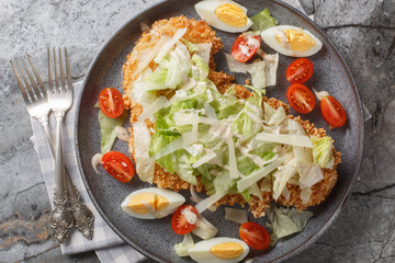 Delicious fresh schnitzel caesar salad with chicken meat, eggs, parmesan, iceberg lettuce and...