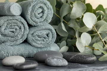 Close-up of rolled towels with spa stones and fresh eucalyptus leaves