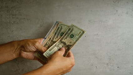 Hands counting american dollars on a concrete background