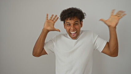 Handsome young hispanic man with curly hair gesturing and smiling enthusiastically over a white...
