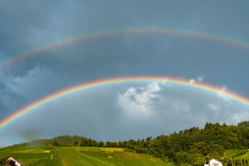 A rainbow is seen in the sky above a hillside
