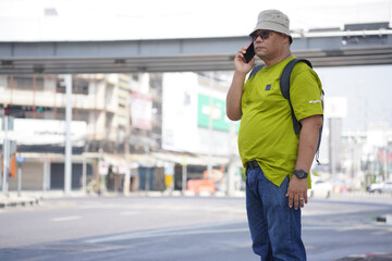 Obraz premium Asian man walking alone in the city street. Mid adult tourist guy on sidewalk one person in urban downtown district travel to destinations. Male pedestrian commuter city life. copy space