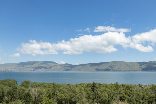 Vibrant scenery of Sevan lake showcases lush greenery and distant hills under a captivating sky, inviting exploration.
