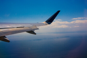 Fototapeta premium An airplane wing with clear blue sky background flying above Greek islands