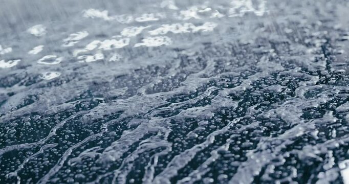 Witness the ultimate in paint protection as water beads up and runs off a car's surface. This close-up shot demonstrates the effectiveness of a high-quality wax or sealant.