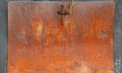 Closeup of an old and totally rusty metal sheet on a black wall as a background with copy space