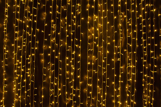 Sparkling led yellow lights running vertically. A curtain of Christmas fairy lights. Fairy light strips - Powered by Adobe