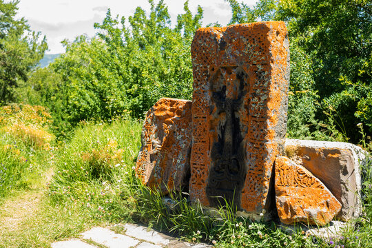 Stunning khachkar stones stand out amid lush greenery, highlighting Armenian heritage at Sevanavank Monastery.