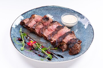 Medium-Rare Grilled Steak Sliced with Sauce on a Plate on a White Background