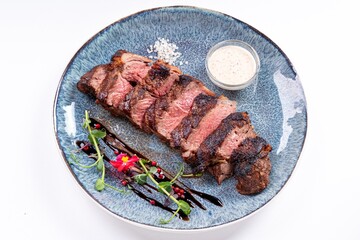 Medium-Rare Grilled Steak Sliced with Sauce on a Plate on a White Background