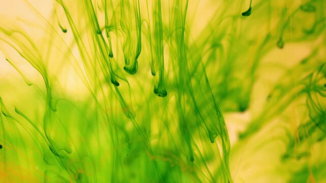 Green ink breaks up in water creating abstract structures, inky background