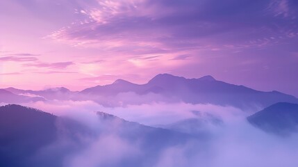 Fototapeta premium The sky is a beautiful shade of purple with clouds floating above. The mountains in the background are covered in fog, creating a serene and peaceful atmosphere