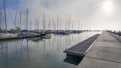Obraz premium Serene marina with docked yachts under a misty sky, perfect for concepts of tranquility and coastal travel