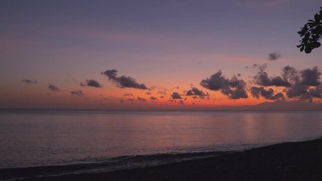 On sea shore looking at calm sea and red sky before sunrise. Location: Amed Bali Indonesia
