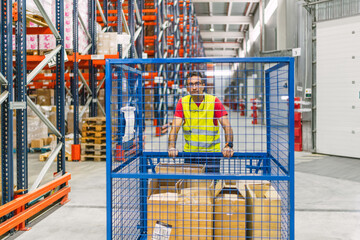 Warehouse worker pushing rolling cage with packages in logistics center