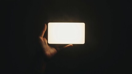 a person holding a white light in their hand against a black background