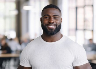 Fototapeta premium A smiling man with a beard stands confidently in a bright, modern workspace, exuding a friendly and approachable vibe.