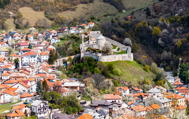 Fototapeta premium Scenic view of Travnik, Bosnia and Herzegovina, featuring historical buildings, mosques with minarets, a clock tower, and a fortress surrounded by lush green hills. A picturesque Balkan town.