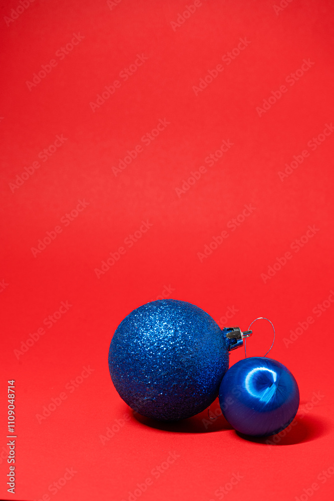 Wall mural Two blue Christmas ornaments on a vibrant red background, creating a festive contrast.