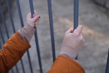 A closeup view of hands gripping metal bars, representing themes of confinement and deep personal contemplation