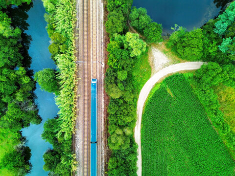 Vista a&eacute;rea de um comboio a passar por uma paisagem agr&iacute;cola. 