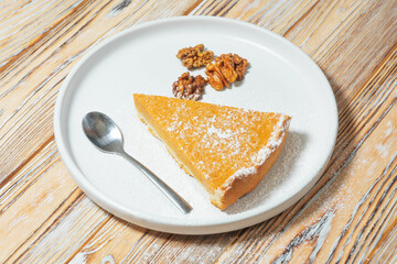 Slice of Pumpkin Pie with Walnuts on a Rustic Table