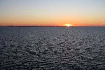 Die Sonne ist an einem sch&ouml;nen Sommertag teilweise untergegangen &uuml;ber dem Kattegat. Es gibt nur wenige Wellen, und die untergehende Sonne taucht den Himmel in orangefarbenes Licht.