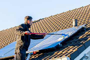 man holding mop cleaning solar panels. cleaning of solar modules with water. close-up of solar...