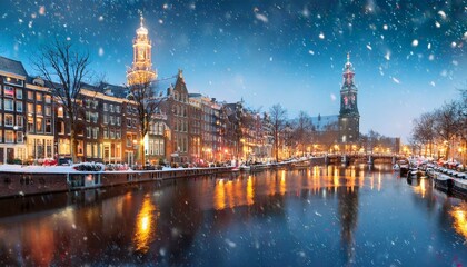 Fototapeta premium enchanting winter cityscape of amsterdam with snow falling over illuminated historic buildings and church spires reflected in calm canal waters at dusk