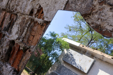 Reflection in a Broken Mirror on an Old Brick Wall. A creative composition featuring a shattered...