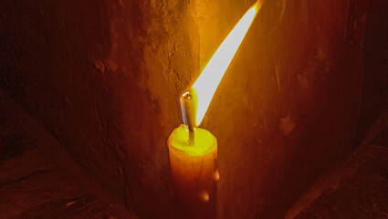 A candle lit in a room in a house that is experiencing a power outage.
