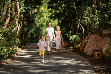 Fototapeta premium A joyful family walking together through lush greenery, enjoying the fresh air and peaceful atmosphere of nature.
