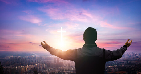 Fototapeta premium Religious concept. Young man praying with cross on sky background.